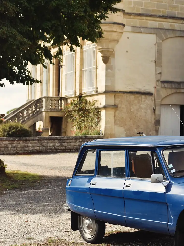 Une Citroën bleue ancienne garée dans la cour du château